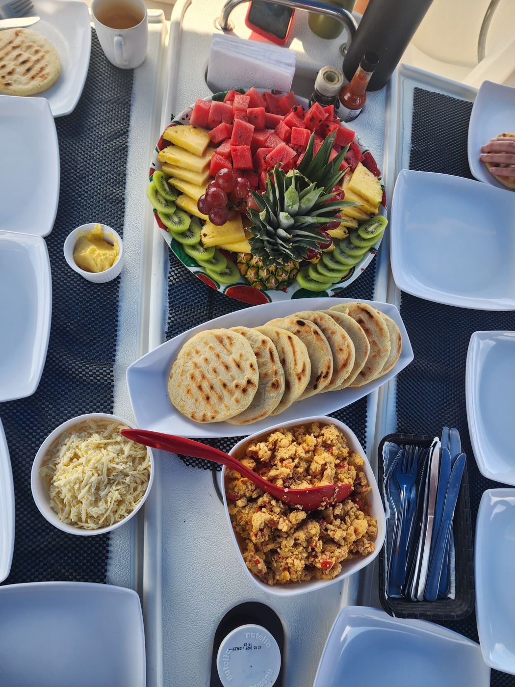 Breakfast spread with waffles, fruit and eggs on the boat table
